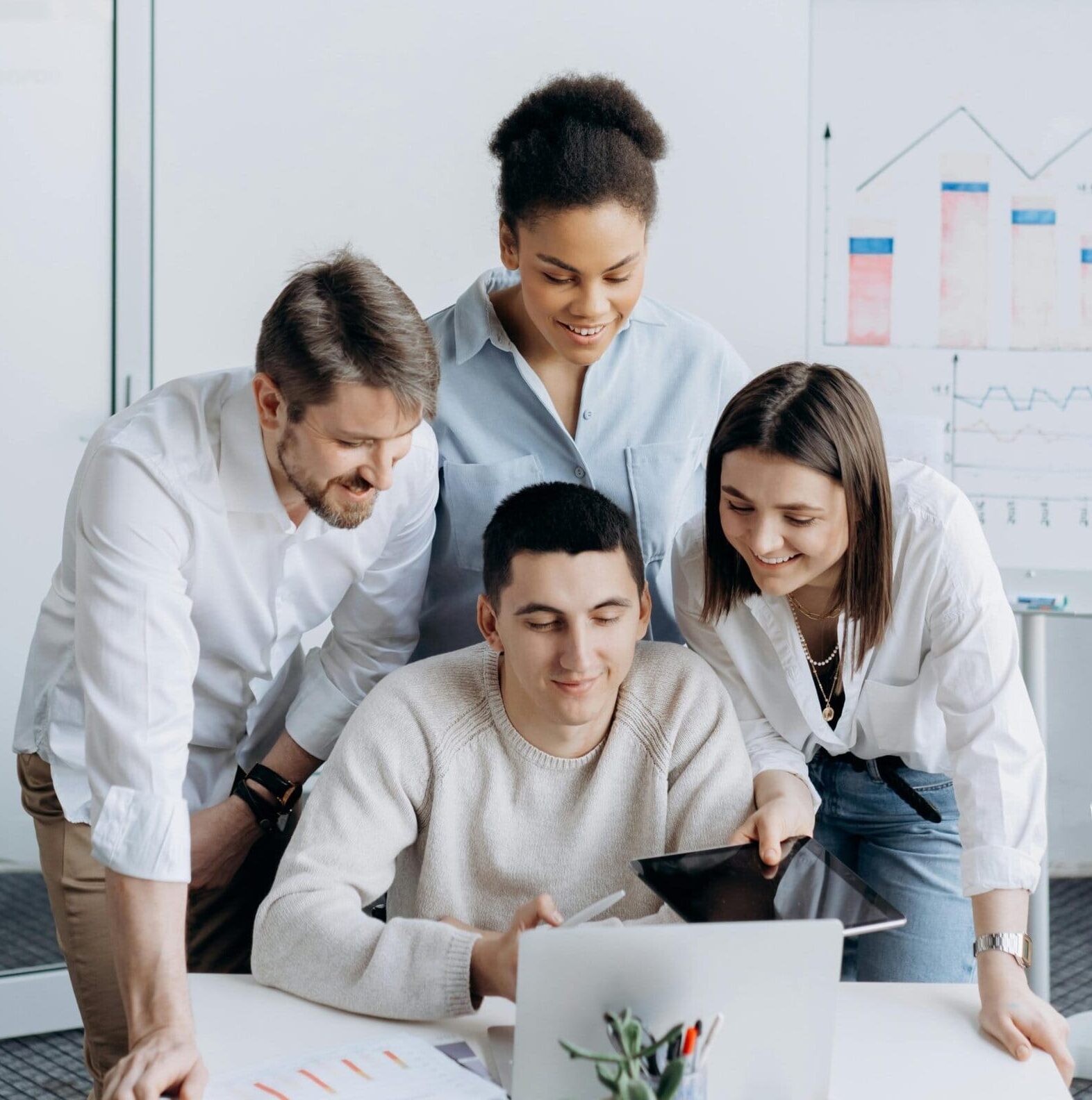 Ein Mann und zwei Frauen schauen über die Schultern eines Mannes in einem Büro